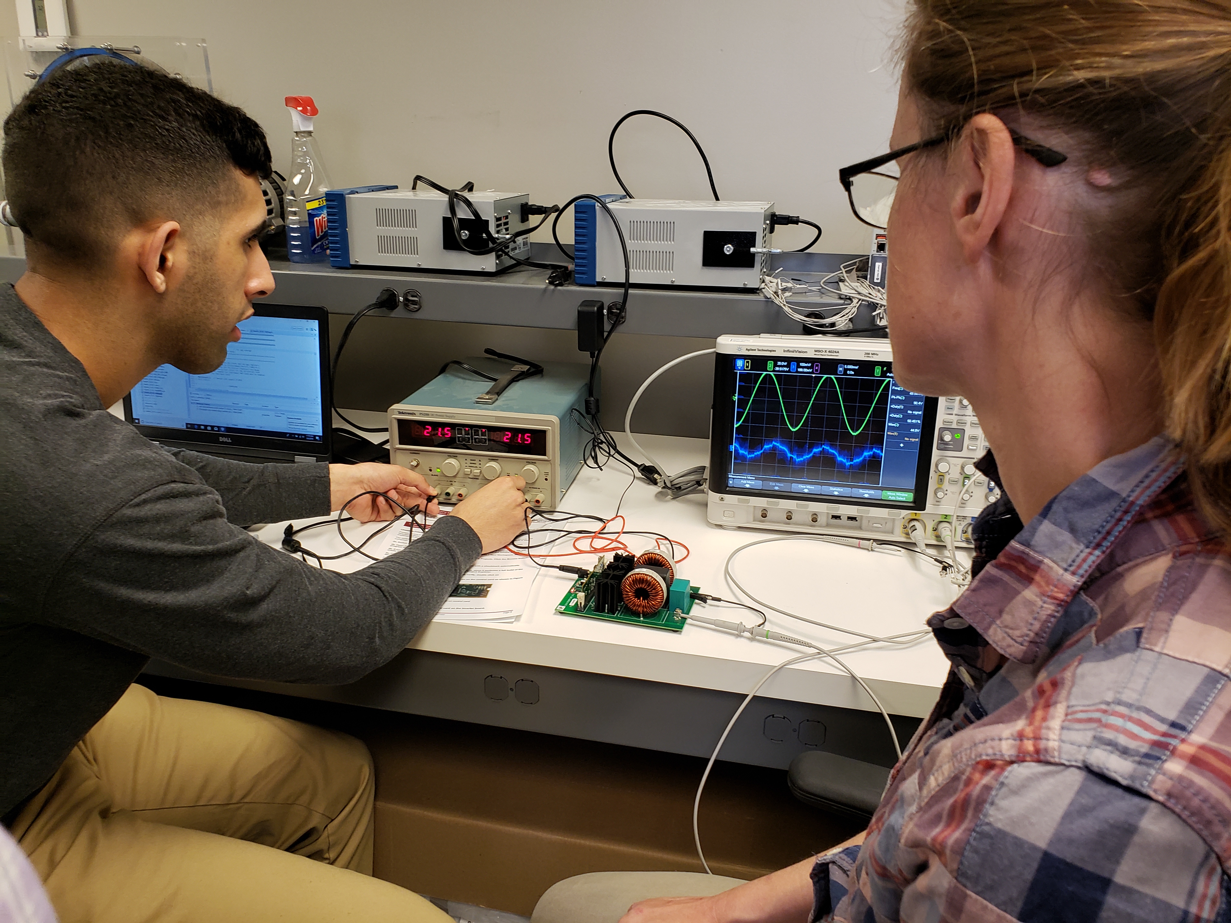 Image of two trainees taking measurements using an oscilloscope.